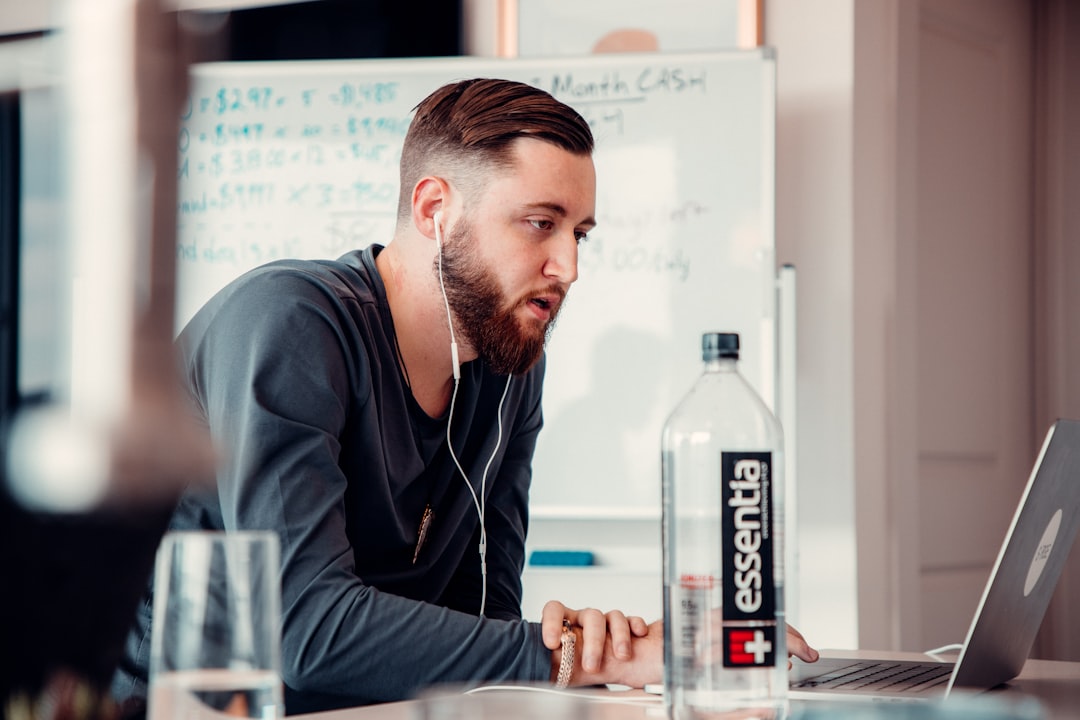 a man sitting at a table looking at a laptop